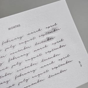 May include: A white sheet of paper featuring the word MONTHS in a sans-serif font at the top, followed by rows of months written in a black cursive script. The text 1521 STUDIO appears at the bottom, and the code SS-1A is printed on the right side.