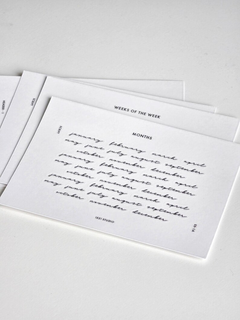 May include: A stack of white rectangular cards featuring black printed text. The top card displays the word MONTHS in a sans-serif font above a list of months written in a cursive script. The text 1521 STUDIO and SS-1A are printed at the bottom.
