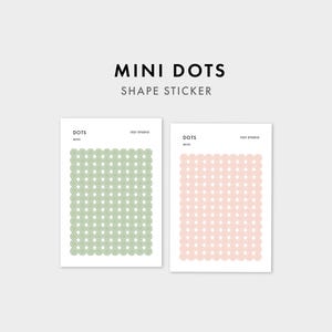 Może przedstawiać: Dwa prostokątne arkusze naklejek w kształcie mini kropek z napisem MINI DOTS SHAPE STICKER. Jeden arkusz zawiera siatkę szałwiowo-zielonych okrągłych naklejek, a drugi siatkę jasnoróżowych okrągłych naklejek, oba oznaczone jako 1521 STUDIO.