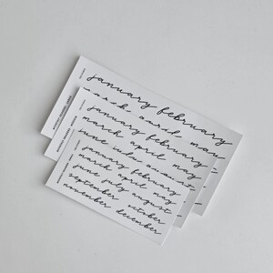 May include: Three white rectangular cards stacked vertically, each featuring black handwritten-style text listing months of the year. The cards are labelled Monthly Headers Large, Medium, and Small, with the text January through December printed in a lowercase script font.