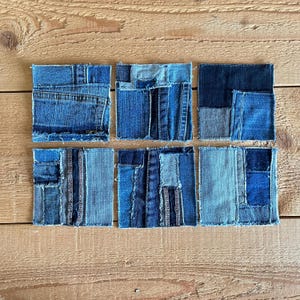 May include: Six blue denim coasters made from repurposed denim fabric. Each coaster is a patchwork of different shades of blue denim, creating a unique and rustic look.