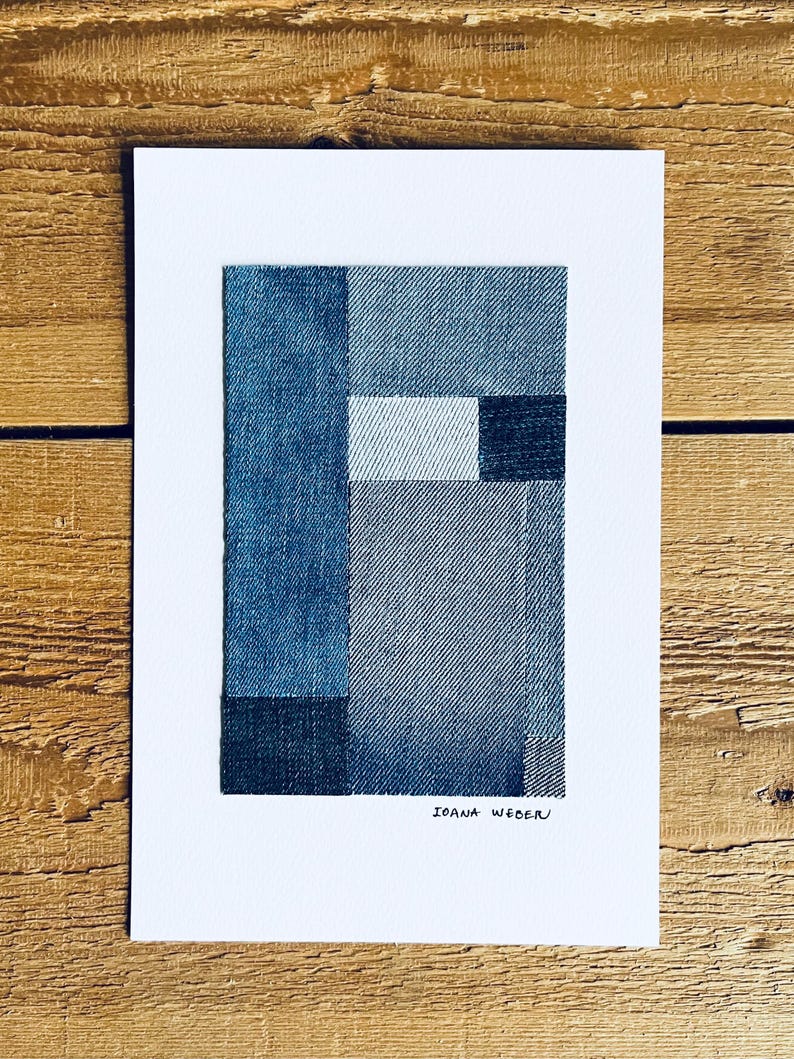 May include: A minimalist abstract art print featuring a geometric design made of different shades of blue denim fabric. The print is signed "Ioana Wede" in the bottom right corner.