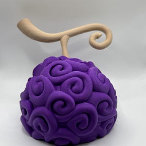 May include: A purple and brown 3D printed model of a fruit with a swirl pattern. The fruit has a stem with a curl at the end.