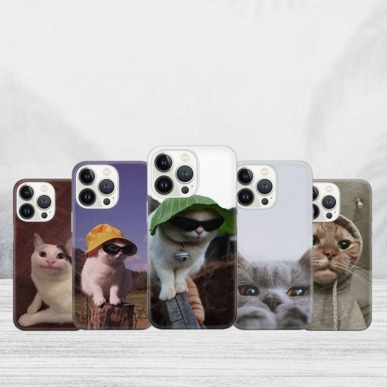 May include: Five iPhone cases with different cat designs. The cases are white with a black camera bump. The cats are wearing sunglasses and hats.