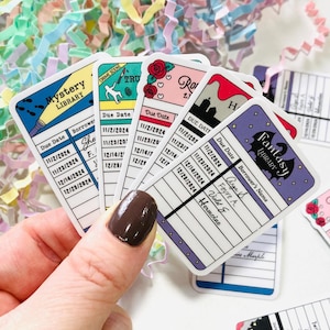 May include: A set of colourful library card stickers with different genres, including mystery, true crime, romance, fantasy, and horror. Each sticker features a unique design and includes a due date and borrower's name section.