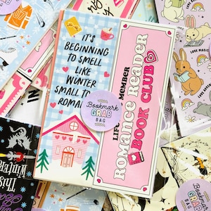 Op de afbeelding: Een verzameling kleurrijke bladwijzers met diverse ontwerpen. Eén bladwijzer leest "It's Beginning to Smell Like Winter Small to Romai" met een huisillustratie. Een andere zegt "Romance Reader Book Club". Andere tonen konijnen, sport en winterthema's.