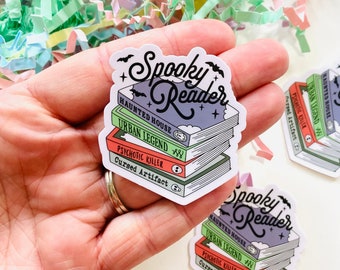 Op de afbeelding: Een sticker met een stapel boeken waarop "Spooky Reader" staat. De titels van de boeken zijn "Haunted House", "Urban Legend", "Psychotic Killer" en "Cursed Artifact".