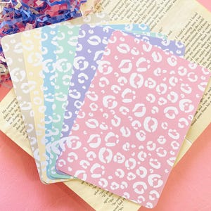 Puede incluir: Una taza de cerámica blanca con un asa negra y el texto "But First, Coffee" en un estilo manuscrito. La taza está sobre una superficie blanca. La taza mide aproximadamente 10 cm de alto.