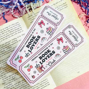Może przedstawiać: Dwie r&oacute;żowe zakładki w kształcie biletu z zaokrąglonymi rogami. Zakładki mają napis "lifetime membership to the BOOK LOVERS Club" oraz ilustracje wiśni, tęczy i książek.
