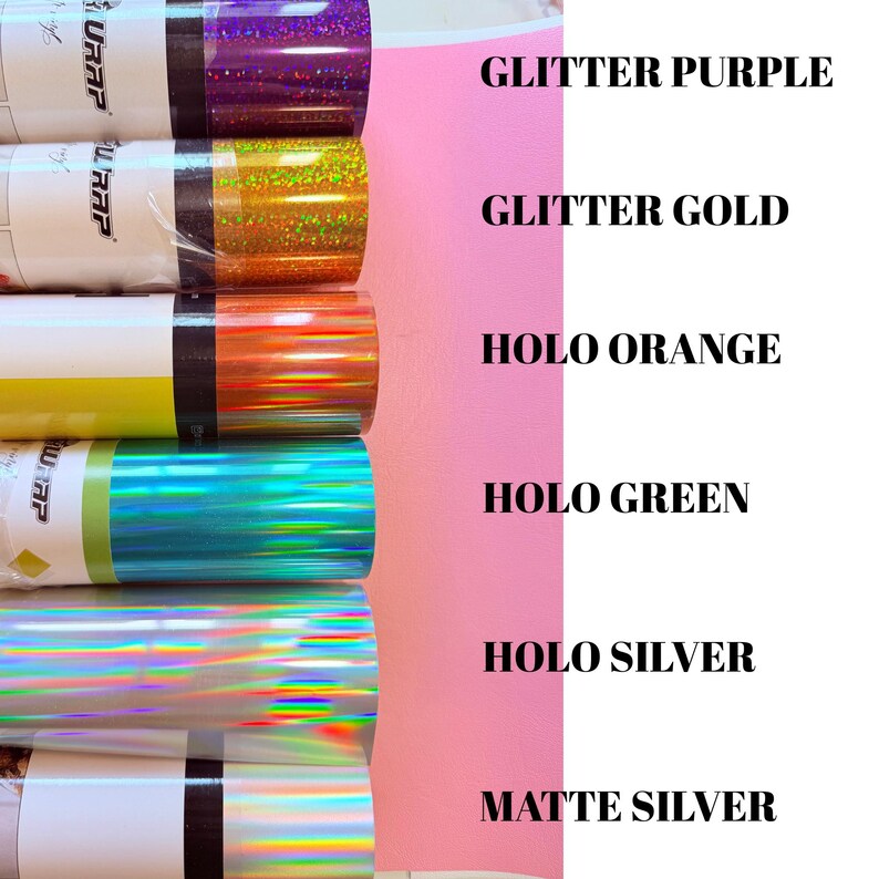 May include: Six rolls of adhesive vinyl wrap arranged vertically, featuring various finishes: glitter purple, glitter gold, holo orange, holo green, holo silver, and matte silver. Each roll is labeled with its corresponding color and finish name.