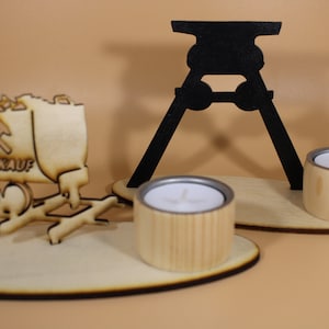 Könnte beinhalten: Ein Kerzenhalter-Set aus Holz mit zwei Teelichtern. Das Set enthält eine schwarze Silhouette eines Grubenwagens und einen Grubenwagen aus Holz mit dem Text "Glückauf" an der Seite.