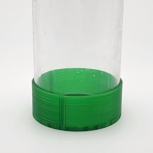 May include: A clear glass jar with a green plastic lid. The lid has a textured surface.
