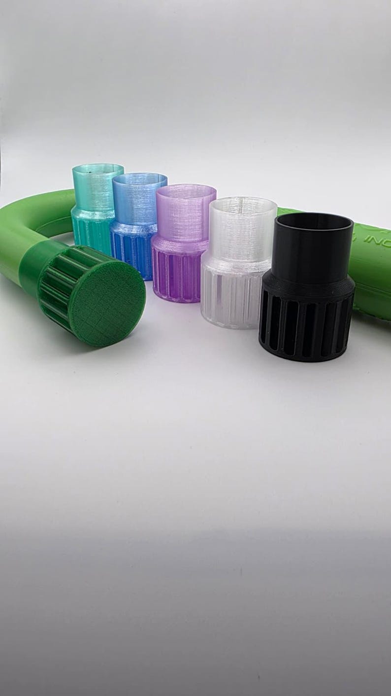 May include: A collection of colorful, cylindrical plastic adapters in various colors, including teal, blue, purple, clear, and black. A green hose is visible on the left and right sides of the image. The adapters have a ribbed design.