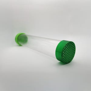 May include: A clear plastic tube with green end caps. One end cap has a honeycomb pattern.