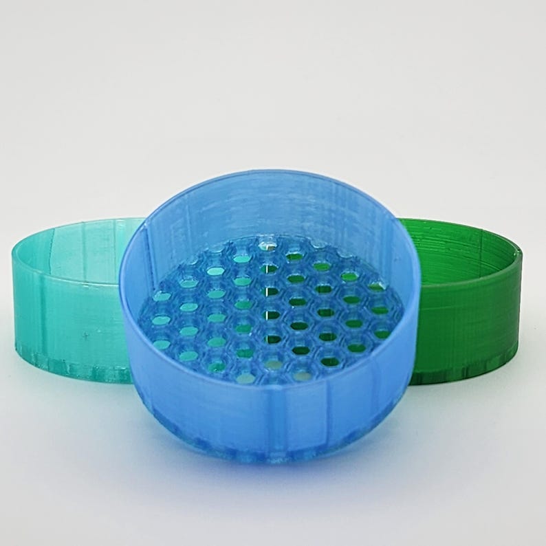 May include: Three plastic containers with a honeycomb pattern on the bottom. The containers are blue, green, and light green.