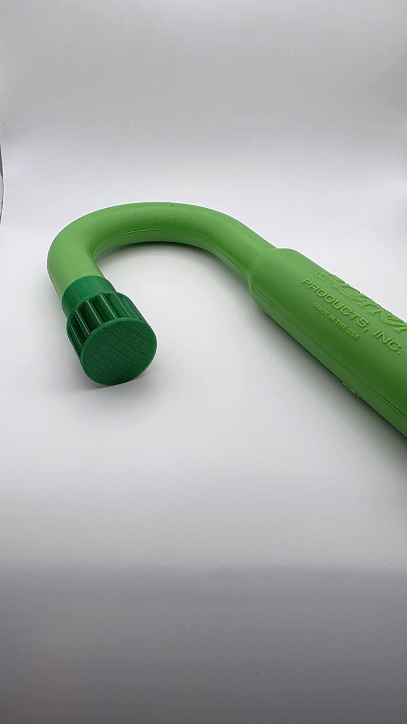 May include: A green, curved cane-shaped product with a textured, dark green cap. The product is made of a solid, smooth material. The text "PRODUCTS, INC. MADE IN THE USA" is printed on the side.