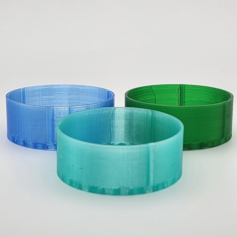 May include: Three round plastic containers in different colors: light blue, teal, and green. The containers are all the same size and shape.