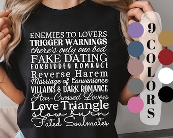 Könnte beinhalten: Ein schwarzes T-Shirt mit weißem Text, der "Enemies to Lovers, Trigger Warnings, there's only one bed, Fake Dating, Forbidden Romance, Reverse Harem, Marriage of Convenience, Villains & Dark Romance, Star-Crossed Lovers, Love Triangle, Slow Burn, Fated Soulmates" lautet. Das Shirt wird von einer Person getragen. Rechts neben dem Shirt befinden sich neun Farbmuster.
