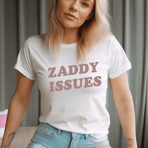 May include: White t-shirt with the text "ZADDY ISSUES" printed in pink.