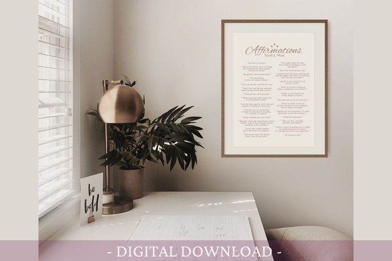 K&ouml;nnte beinhalten: Ein gerahmter Druck mit dem Text "Affirmations" in einer kursivschrift. Der Druck ist auf cremefarbenem Hintergrund mit rosa Text. Der Rahmen ist aus braunem Holz.
