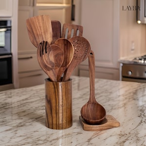 Könnte beinhalten: Ein Satz Küchenutensilien aus Holz in einem braunen Holzhalter. Die Utensilien umfassen einen Schöpflöffel, eine Schöpfkelle, einen Spatel und ein paar Löffel. Der Halter ist aus Holz mit einer dunkelbraunen Oberfläche.