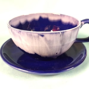 May include: A blue and white teacup and saucer set. The cup has a white glaze with blue streaks and the saucer is a solid blue.