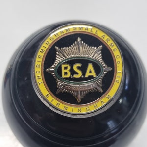 May include: A black and yellow round button with the text "The Birmingham Small Arms Co. Ltd." and a silver star with the text "BSA Motorcycles" in the centre.