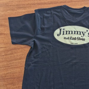 May include: A dark blue t-shirt with a white oval logo that says "Jimmy's Hot Rod Stuff" on the back.