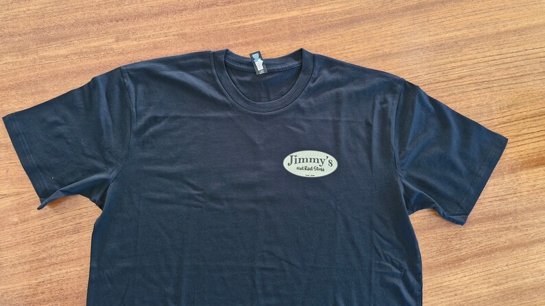 May include: Black t-shirt with a light green oval logo that says "Jimmy's Smoked Meats" on it.