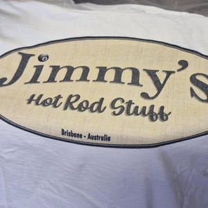 May include: White t-shirt with a tan oval logo that says "Jimmy's Hot Rod Stuff" and "Brisbane - Australia" in black text.