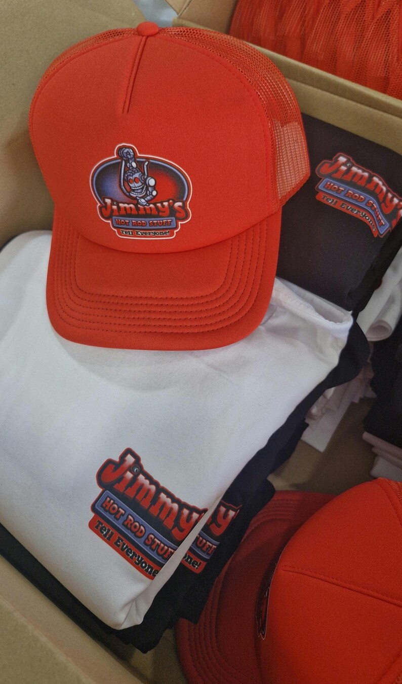May include: Red and black trucker hat with a white logo that says "Jimmy's Hot Rod Stuff Tell Everyone!" The hat is on top of a white t-shirt with the same logo.