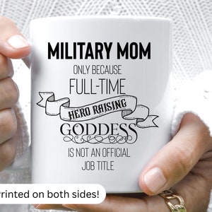 May include: White ceramic coffee mug with black text that reads "Military Mom Only Because Full-Time Hero Raising Goddess Is Not An Official Job Title". The text is in a decorative font with a banner design. The mug is printed on both sides.