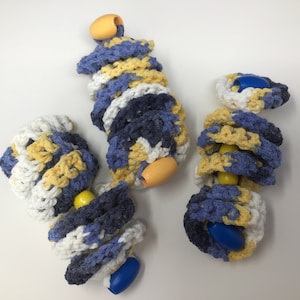 May include: Three crocheted toys in blue, yellow and white with wooden beads. The toys are in the shape of a spiral.