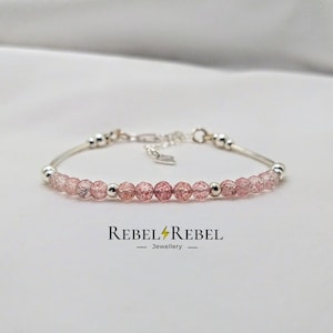 May include: A delicate bracelet featuring a row of pink and clear quartz beads with a silver chain and silver beads. The bracelet is on a white background. Rebel Rebel Jewellery.