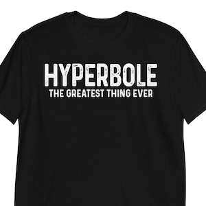 Puede incluir: Camiseta negra con el texto blanco "HYPERBOLE" encima de "THE GREATEST THING EVER". La camiseta está hecha de un material suave, con mangas cortas y cuello redondo.