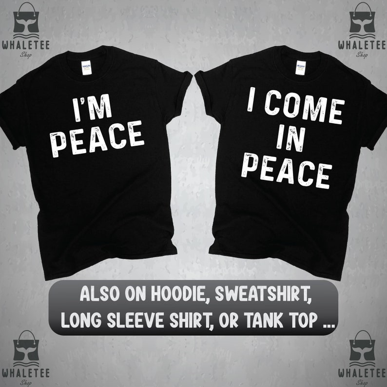 May include: Two black t-shirts with white text. The first shirt says "I'm Peace" and the second shirt says "I Come In Peace".