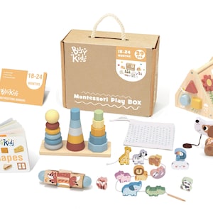 Op de afbeelding: Een houten Montessori-speelbox voor peuters, met een verscheidenheid aan speelgoed, waaronder een vormensorteerder, stapelringen, een trekdier en een kralenlabyrint. De doos is gelabeld "Busy Kids Montessori Play Box" en bevat een boekje met de titel "Shapes".