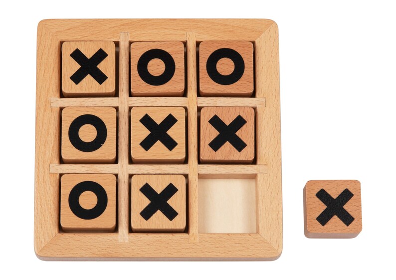 May include: A wooden tic-tac-toe game with nine squares. The squares are filled with wooden tiles that have either an 'X' or an 'O' printed on them. One tile is missing from the game.