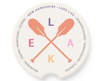 Può includere: Sottobicchiere rotondo bianco con un design "LAKE" rosa, viola e giallo con pagaie arancioni incrociate. Il testo attorno al bordo recita "WAUKEWAN SQUAM NEWFOUND OSSIPEE NEW HAMPSHIRE LAKE LIFE WINNIPESAUKEE WINNISQUAM SUNAPEE".