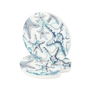 Pu&ograve; includere: Due sottobicchieri in ceramica bianca con un motivo a stelle marine blu e turchese. I sottobicchieri sono rotondi con un bordo a festoni.