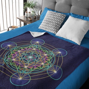 May include: A soft, blue fleece throw blanket with a geometric pattern in shades of gold, green, purple, and blue. The pattern is a complex, overlapping design of circles, lines, and stars.