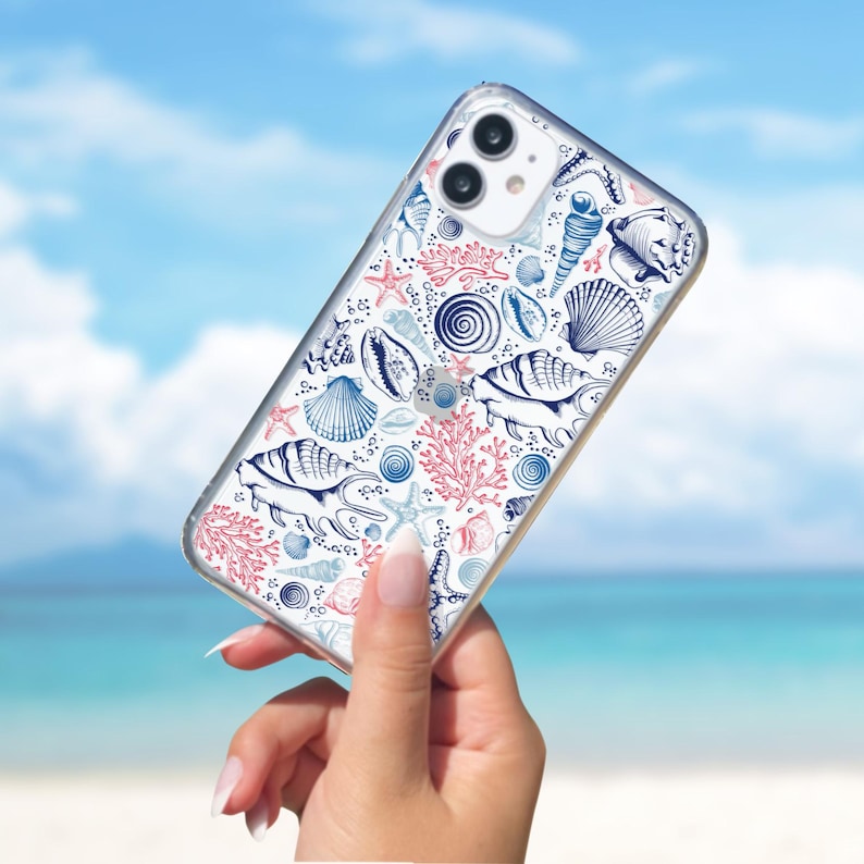 May include: A clear phone case with a white background and a pattern of blue and pink seashells, starfish, and coral.