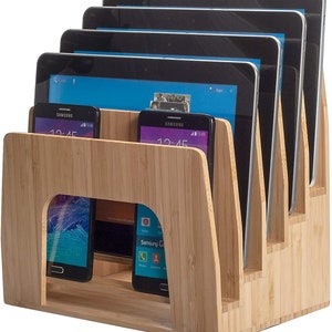 Può includere: Un supporto in bambù con fessure per organizzare tablet e telefoni. Il supporto ha una finitura in legno naturale e può contenere fino a cinque tablet e due telefoni.
