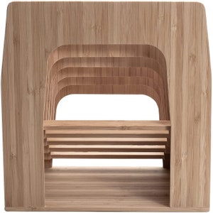 Puede incluir: Un sujetalibros de bamb&uacute; marr&oacute;n claro con una base rectangular y un dise&ntilde;o curvo y en capas. El soporte presenta m&uacute;ltiples listones horizontales para sostener libros y una gran abertura en el centro. La veta natural de la madera es visible.