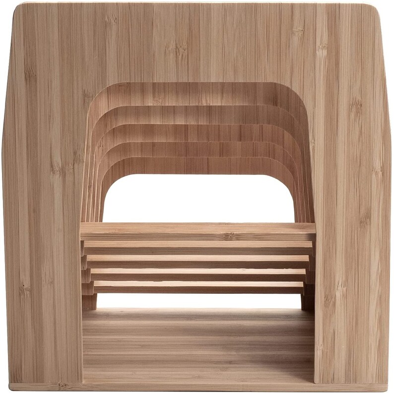 Puede incluir: Un sujetalibros de bamb&uacute; marr&oacute;n claro con una base rectangular y un dise&ntilde;o curvo y en capas. El soporte presenta m&uacute;ltiples listones horizontales para sostener libros y una gran abertura en el centro. La veta natural de la madera es visible.