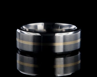 May include: A dark gray titanium ring with a thin gold band around the center.
