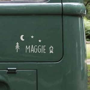 May include: A green van with a white decal that says "MAGGIE" with a moon, stars, a pine tree, and a campfire graphic.