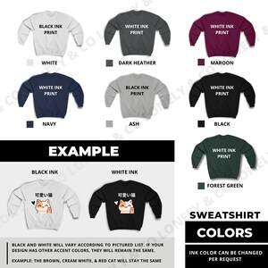 May include: A graphic design for a sweatshirt with a cute cartoon cat wearing a red scarf and holding a heart. The text in Japanese says "kawaii neko" which means "cute cat". The design is available in black ink on a white sweatshirt or white ink on a black sweatshirt. The sweatshirt is available in a variety of colors including white, dark heather, maroon, navy, ash, black, and forest green.
