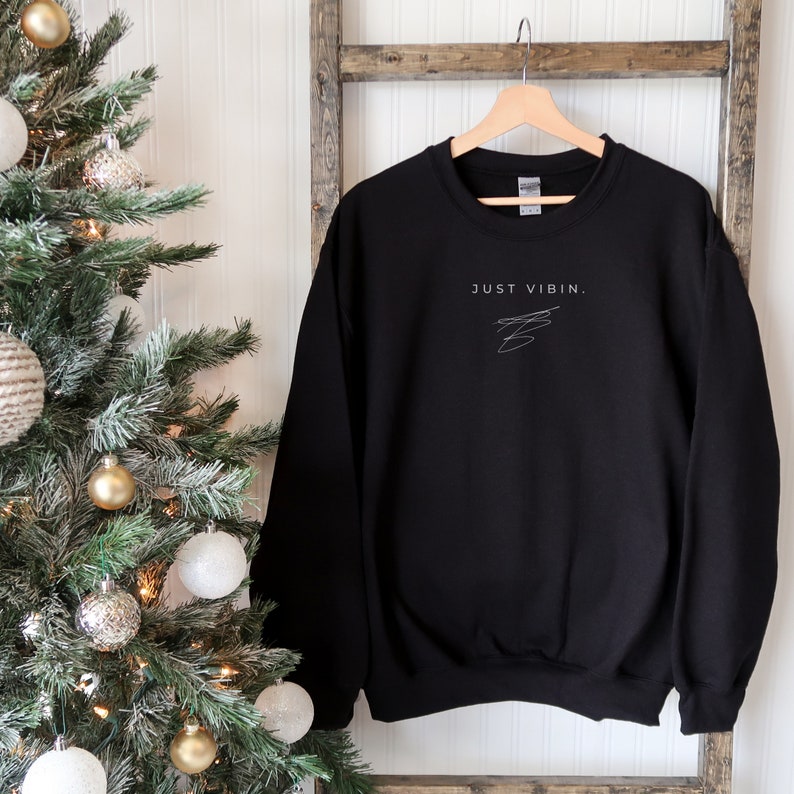 May include: Black sweatshirt with the text "JUST VIBIN." in white lettering and a simple white line drawing.