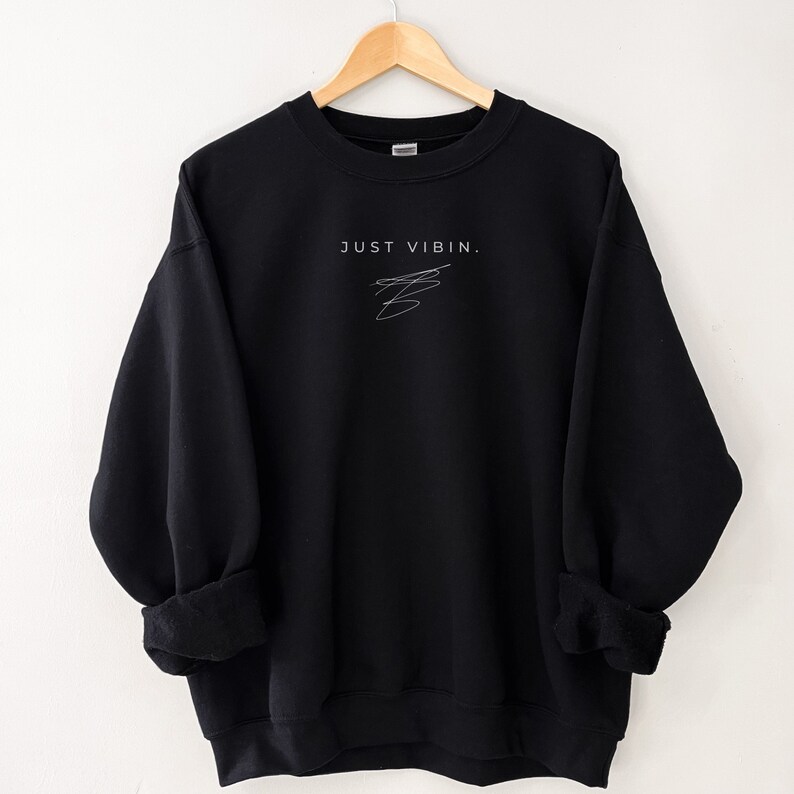 May include: Black sweatshirt with the text "JUST VIBIN." in white lettering and a simple white doodle.